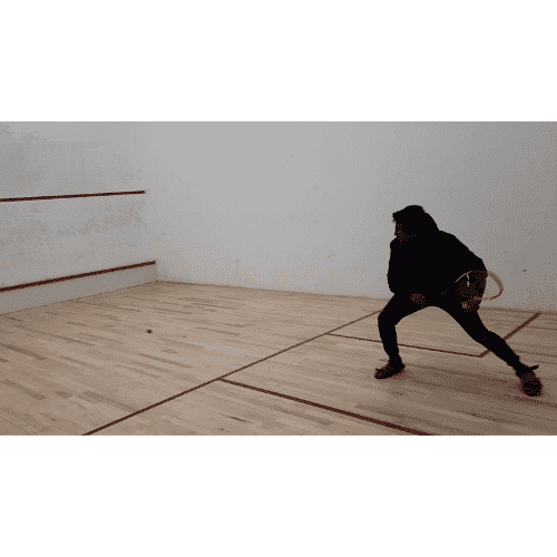 Akshet Patel playing squash on an indoor court